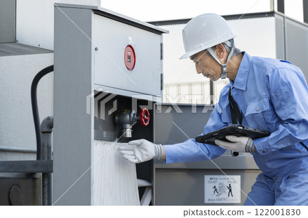 A veteran worker inspecting outdoor fire hydrant equipment 122001830