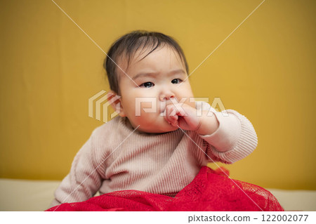 黃色背景中坐著一個淚眼汪汪的嬰兒 122002077