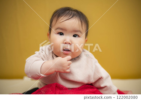 黃色背景中坐著一個淚眼汪汪的嬰兒 122002080