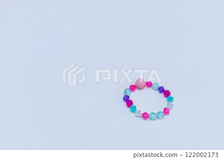 Kids handmade beaded jewelry. Necklaces and bracelets made from multicolored beads and pearls on a pastel background. DIY Multi-colored bracelet beads. Children's needlework. Kids handmade beaded jewelry. Necklaces and bracelets made from multicolored beads and pearls on a pastel background. DIY Multi-colored bracelet beads. Children's needlework. 122002173