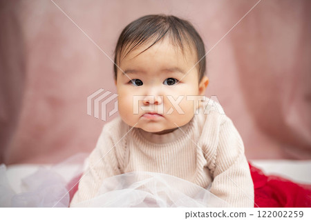 嬰兒坐在粉紅色的背上 嬰兒坐在粉紅色的背上 122002259