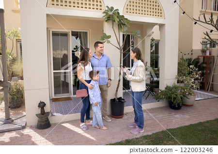 Real estate broker woman meeting with family on front yard Real estate broker woman meeting with family on front yard 122003246