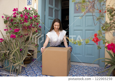 Happy young customer woman taking awaited parcel from doorstep 122003250