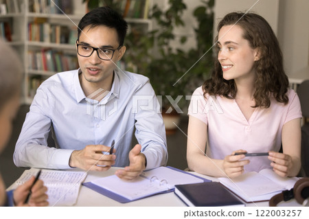 Smiling teen female student listen to young male groupmate speaking 122003257