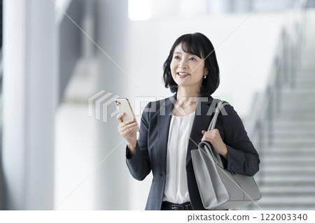 一位 50 歲出頭的女商人，擁有智慧型手機 122003340