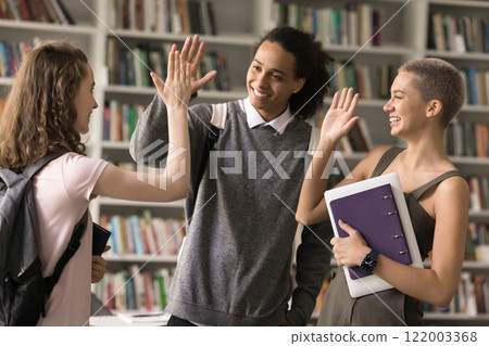 Excited diverse teenage ethnic students join palms in high five 122003368