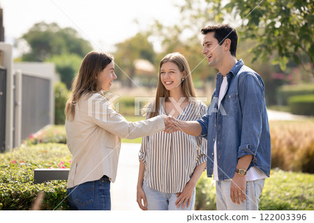 Happy young couple and real estate insurance agent shaking hands 122003396