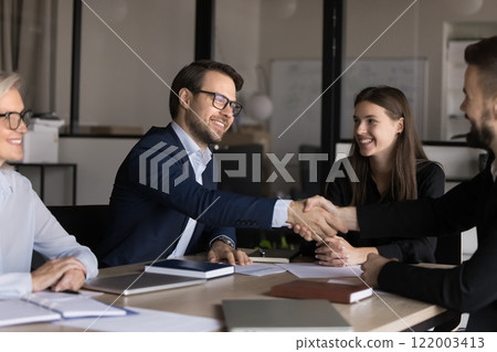 Smiling male colleagues, shareholders shake hands close deal at meeting 122003413