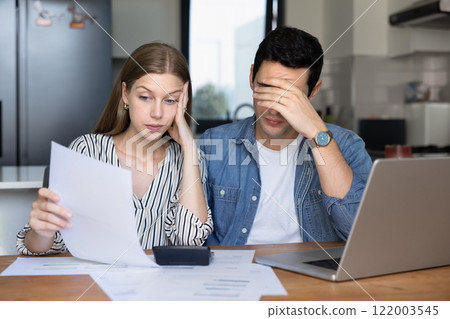 Concerned young couple of renters checking too high paper bills 122003545