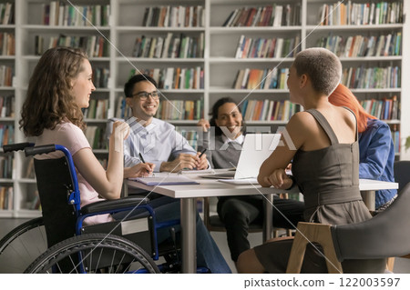 Young female using wheelchair chatting having fun with diverse classmates 122003597