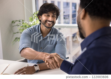 Cheerful young Indian professional man shaking hands with business partner 122003606