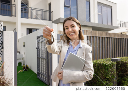 Happy real estate agent woman offering key from new home Happy real estate agent woman offering key from new home 122003660