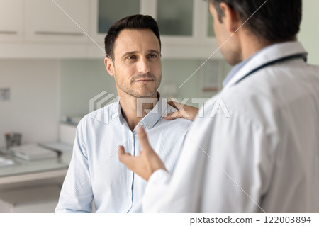 Male clinic patient listening to doctor in hospital office 122003894