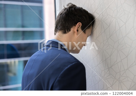 Exhausted depressed manager man leaning head on wall 122004004