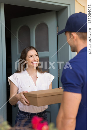 Happy customer woman taking cardboard box from courier Happy customer woman taking cardboard box from courier 122004081