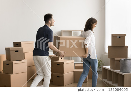 Couple bringing cardboard boxes with personal belongings into living room Couple bringing cardboard boxes with personal belongings into living room 122004095