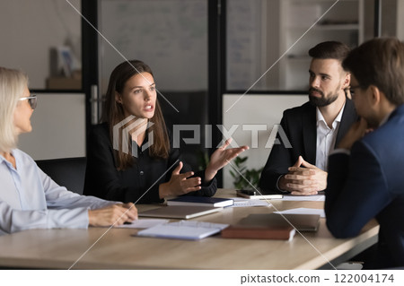 Serious young and mature colleagues brainstorm at conference table 122004174