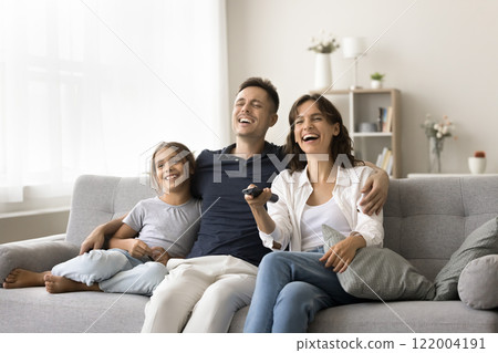 Happy parents with daughter sitting watching favourite television show Happy parents with daughter sitting watching favourite television show 122004191