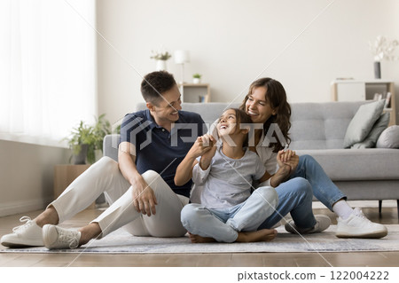 Happy family sitting on warm floor in cozy living room 122004222