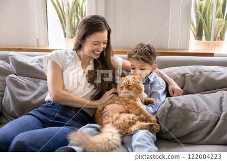 Happy mother cuddling little son boy and furry orange cat 122004223