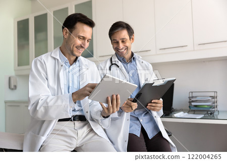 Two positive medical colleagues discussing electronic report Two positive medical colleagues discussing electronic report 122004265