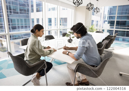 Two Indian business colleagues discussing job case at meeting table Two Indian business colleagues discussing job case at meeting table 122004316