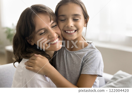 Close up of lovely little girl cuddling tightly her mother 122004420