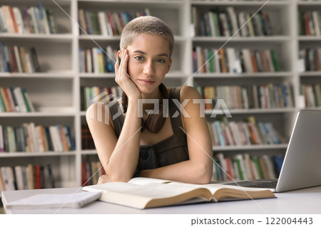 Portrait smart stylish teen female studying at desk in library 122004443