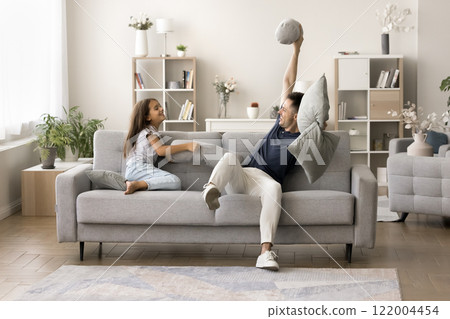 Happy young father and energetic daughter fighting with cushions 122004454