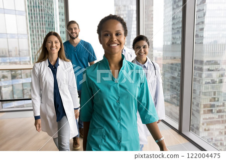 Doctors walking across clinic hallway led by African female colleague Doctors walking across clinic hallway led by African female colleague 122004475