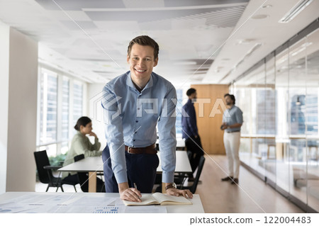 Positive confident business leader man posing in open office Positive confident business leader man posing in open office 122004483