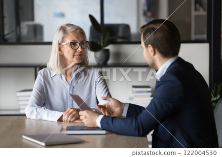 Two colleagues discussing project marketing strategy in office 122004530