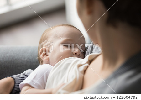 Closeup portrait cute little infant sleep in caring mom arms 122004792