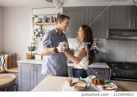 Cheerful young couple in love dancing at kitchen table 122004802