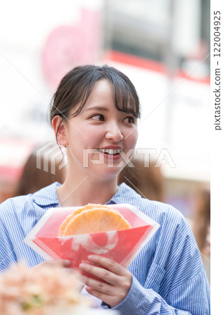 大阪道頓堀，一位女士一邊走一邊吃著名的章魚線。 122004925