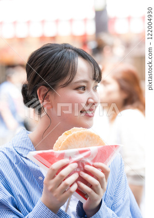 大阪道頓堀,一位女士一邊走一邊吃著名的章魚線。 大阪道頓堀,一位女士一邊走一邊吃著名的章魚線。 122004930