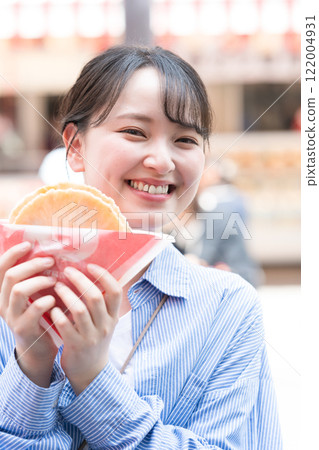 A woman eating the famous takosen (octopus crackers) as she walks through Dotonbori, Osaka A woman eating the famous takosen (octopus crackers) as she walks through Dotonbori, Osaka 122004931