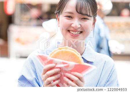 大阪道頓堀，一位女士一邊走一邊吃著名的章魚線。 122004933