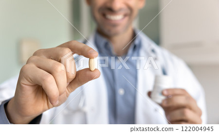 Hands of positive male doctor holding pill and bottle 122004945