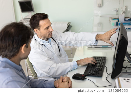 Serious medical specialist showing examination report on computer 122004963
