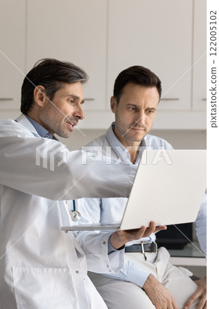 Serious middle aged practitioner doctor showing medical report to patient Serious middle aged practitioner doctor showing medical report to patient 122005102