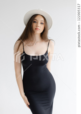 Girl with long hair with white hat is standing on white studio background Girl with long hair with white hat is standing on white studio background 122005317