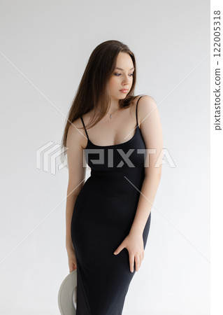 Girl with long hair with white hat is standing on white studio background 122005318