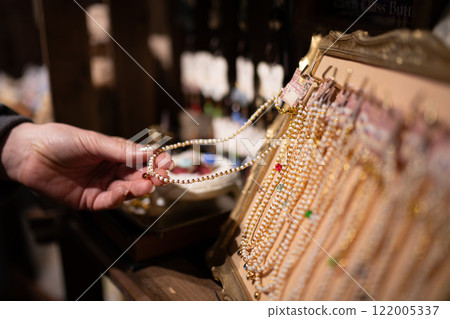 Woman's hands choosing a necklace 122005337
