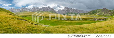 panorama of wide green valley in highlands of kyrgyzstan high mountains in the background, countryside suitable for grazing cattle 122005635
