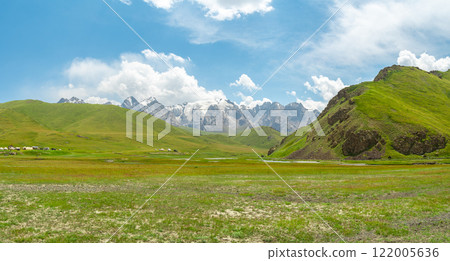 panorama of wide green valley in highlands of kyrgyzstan high mountains in the background, countryside suitable for grazing cattle 122005636