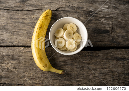 Cup of banana slices next to a whole banana 122006270