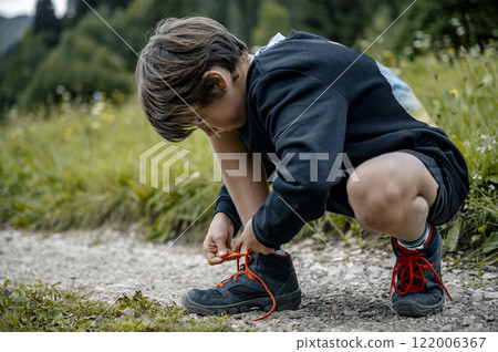Child tying shoelaces outdoors 122006367