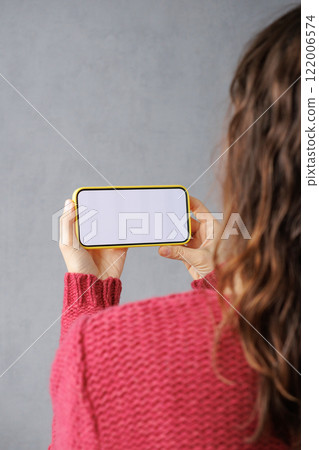 close-up image of woman in pink sitting indoors and using her smartphone. mock-up 122006574