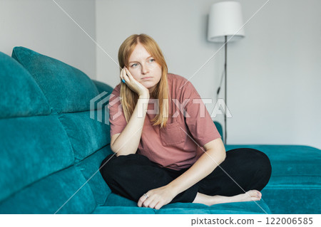 Bad day. Frustrating young 30s female siting on the sofa. Cheerful 30s woman sit on couch spending time in living room at home. Full body 122006585